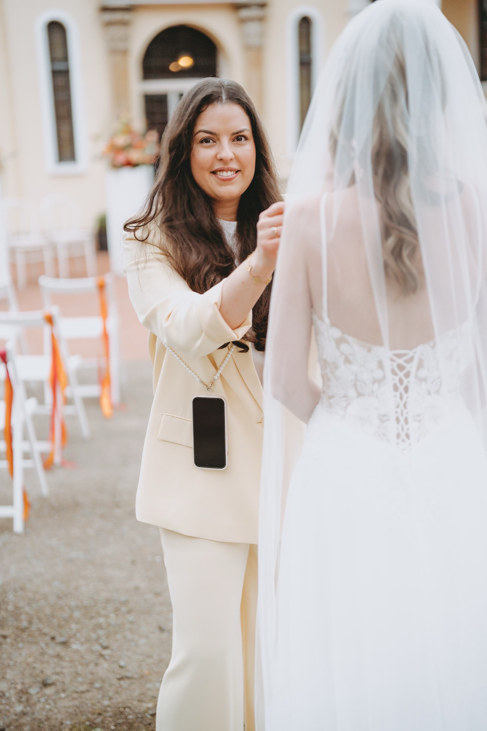 Hochzeitsplanerin Janice von Beleza Weddings & Events richtet den Schleier der Braut kurz vor der Outdoor-Zeremonie