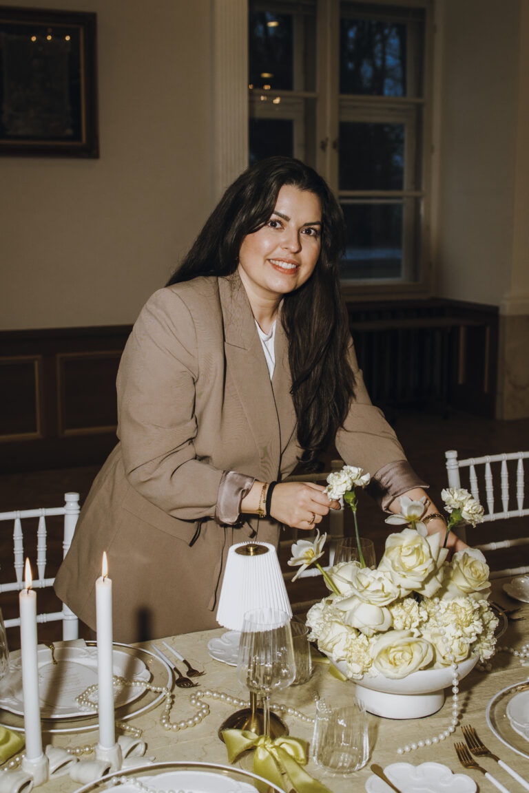 hochzeitsplanerin richtet die tischdekoration und lächelt in die Kamera- beleza weddings und events